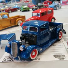 an assortment of model cars on display at a car show, including one blue truck and the other red