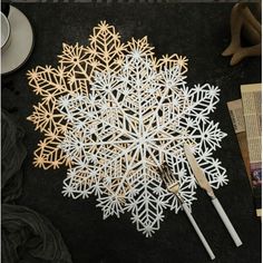 paper snowflakes are laid out on a table with utensils next to them