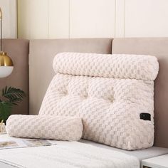 a couch with a pillow on top of it next to a lamp and plant in the corner