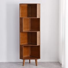 a tall wooden shelf with three shelves on each side, against a white wall in an empty room