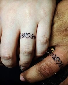 two people with tattoos on their fingers and one is holding the other's hand