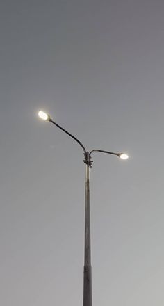 a street light with two lights on top of it in front of a gray sky