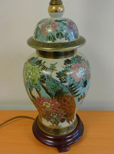 a vase with a bird painted on it sitting on a table next to a lamp