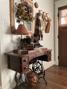 an old sewing machine is sitting in front of a wooden table with a lamp on it