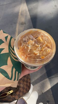 a person holding a starbucks drink in their left hand with sunglasses on the other side