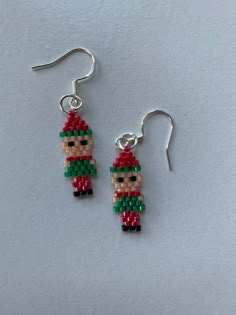 a pair of beaded earrings with a little elf on it's earwires