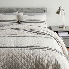 a bed with white and black bedspread next to a lamp on a table