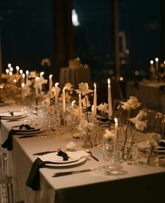 a long table is set with white flowers and candles for an elegant dinner or party