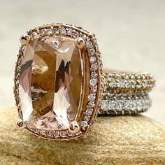 two gold rings with an orange and white stone surrounded by diamonds on top of a rock