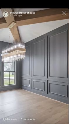 an empty room with wood flooring and gray painted walls, chandelier hanging from the ceiling