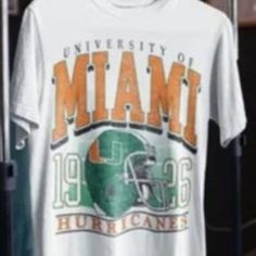 Vintage Miami Hurricanes Shirt, University Of Miami Shirt, Unisex T-Shirt - Nba T-Shirt, Oversized Shirt, Graphic Tee Product Information Promise That You Will Get The Best Products We Have. With Variety Of T Shirts Styles, Sizes And Colors. Detail T-Shirt: 100% Premium Cotton Short Sleeve Unisex T-Shirt. Suitable For Ladies And Gentlemen. Natural And Organic Dyes Are Used And No Harmful Effects To Human Health. Fabric Weight: 5.0 Oz (Mid-Weight). Double-Stitched Seams At Shoulder, Sleeve, Colla White Graphic Tee For College, Collegiate White T-shirt With Text Print, White Collegiate T-shirt With Text Print, Collegiate Short Sleeve Tops With Sublimation Print, Fan Merchandise Short Sleeve Shirt With Text Print, Short Sleeve Shirt With Text Print For College, College Text Print Short Sleeve Shirt, White Text Print Top For Fan Merchandise, White Team Spirit T-shirt For Summer