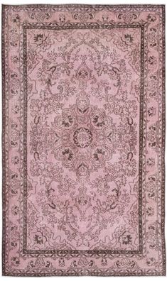 a pink rug with an ornate design on the center and sides, in various colors