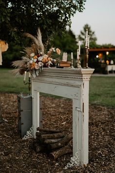 an old fireplace with candles and flowers on it