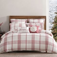 a red and white plaid comforter set in a bedroom with christmas tree behind it