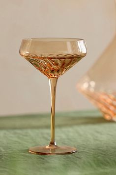 an empty wine glass sitting on top of a green tablecloth next to a vase