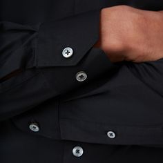 The James solid OoohCotton shirt features a point collar, adjustable notched cuffs, mother-of-pearl buttons, and a curved hem perfect for wearing tucked or untucked. OoohCotton is a performance, double-mercerized, wrinkle-resistant, breathable, and easy-care cotton blend with 8-way stretch, quick-dry, and thermal comfort properties. Timeless Tops With Buttons And Fold Down Collar, Elegant Solid Dress Shirt With Button Cuffs, Formal Solid Tops With Button Cuffs, Formal Solid Color Tops With Buttons, Tailored Button-up Shirt, Solid Color Collared Shirt With Functional Buttons, Formal Black Tops With Buttons, Modern Semi-formal Tops With Button Cuffs, Solid Color Shirt With Fold Down Collar And Buttons