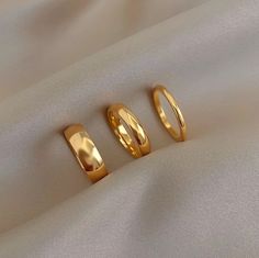 three gold rings sitting on top of a white cloth