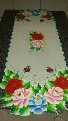 a table with flowers painted on it in the middle of some tile flooring next to a wall