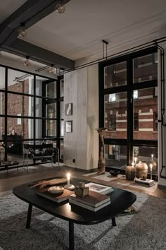 a living room filled with lots of windows next to a table and two lit candles