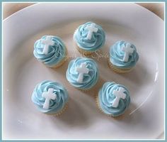 cupcakes with blue frosting and white crosses on them sitting on a plate