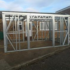 a metal structure sitting on the side of a road next to a building with windows