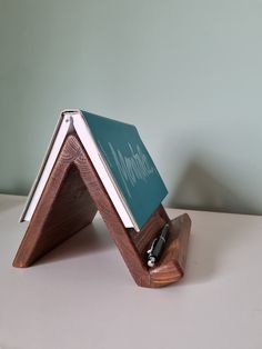 a wooden stand with a notepad and pen on it that is shaped like a triangle