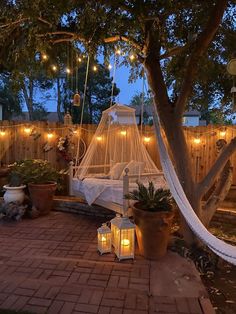 a white bed sitting in the middle of a yard next to a tree with lights on it