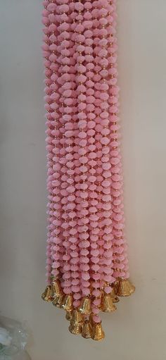 some pink and gold beads hanging from a wall