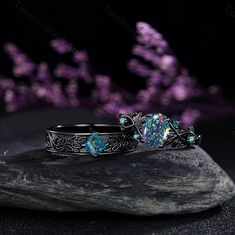 two rings sitting on top of a rock with purple flowers in the background and one is blue