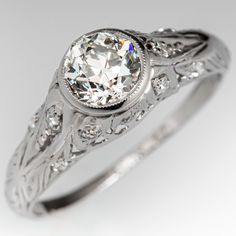 a white gold ring with an old - fashioned design and round cut diamond in the center