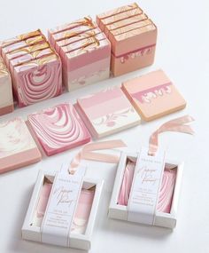 pink and white boxes with gold foil designs on them are sitting next to each other