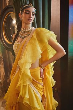 Mango pre-stitched saree with ruffle detail and embroidered border. Paired with floral embroidered blouse.
Component: 2
Embroidered
Neckline: Sweetheart
Sleeve Length: Sleeveless
Fabric: Georgette,Organza
Color: Yellow
Tassel straps
Sequin, pearl and cutdana work - Aza Fashions Elegant Pre-draped Saree With Ruffles For Navratri, Elegant Festive Dupatta With Ruffles, Elegant Ruffled Dupatta For Festive Occasions, Elegant Festival Blouse Piece With Ruffles, Elegant Ruffled Blouse Piece For Festivals, Festival Georgette Pre-draped Saree With Cape Sleeves, Festive Pre-draped Ruffled Saree In Georgette, Elegant Yellow Pre-draped Saree With Traditional Drape, Festive Ruffled Georgette Dupatta