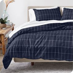 a bed with blue and white comforters in a room next to a wooden table