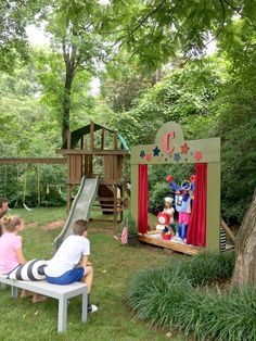 two children are sitting on a bench in front of a play set with clowns