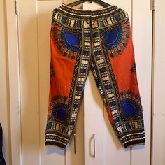 Comfy And Unisex Jamaican African Style Joggers Pants In Size Xl Stretch Orange Pants With Elastic Waistband, Orange Pants With Elastic Waistband For Loungewear, Stretch Orange Pants With Pockets, Stretch Orange Bottoms With Pockets, Bohemian Orange Bottoms With Elastic Waistband, Casual Orange Straight Pants, Orange Bohemian Bottoms With Elastic Waistband, Casual Orange Wide Leg Harem Pants, Bohemian Orange Pants With Elastic Waistband