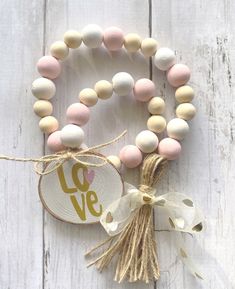 two bracelets with beads and a tag hanging on a white wooden wall next to each other