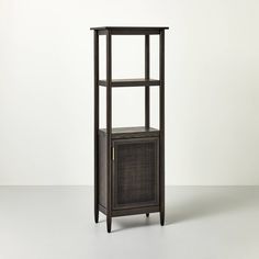 a tall shelf with a basket on top and one door open to reveal a cabinet