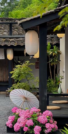 a white umbrella sitting on top of a wooden table next to flowers and plants in front of a building