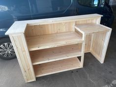 two wooden shelves sitting next to each other in front of a blue van on the street