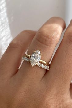 a woman's hand with a diamond ring on top of her finger and an engagement band