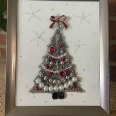 a christmas tree with red and white ornaments in a silver frame on a carpeted floor