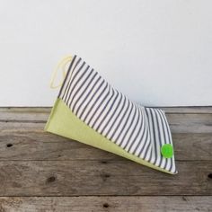 a striped pillow sitting on top of a wooden floor next to a white and green wall