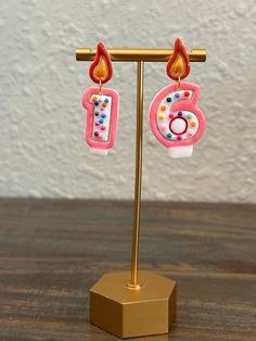 a pair of pink and white birthday candles on a gold plated display stand with a wall in the background