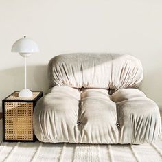 a chair sitting on top of a white rug next to a lamp and a table