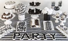 a table topped with lots of desserts and cupcakes covered in black and white frosting