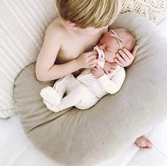 a little boy that is laying down next to a baby