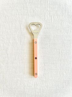 a heart shaped metal bottle opener sitting on top of a white towel