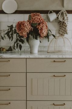 flowers in a white vase sitting on top of a counter