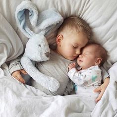 a baby sleeping next to a stuffed animal