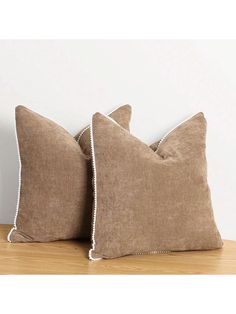 two brown pillows sitting on top of a wooden table